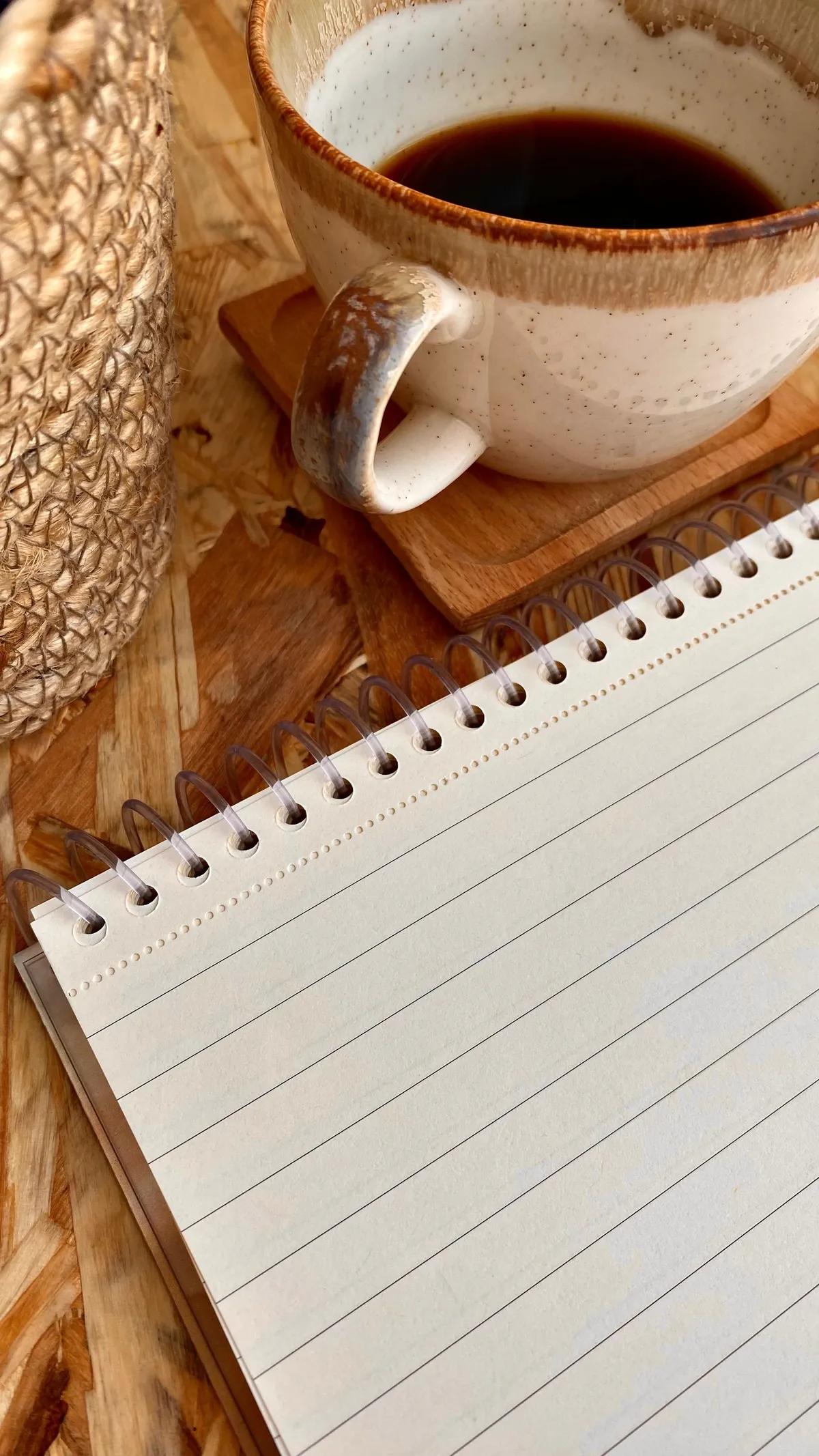 Un quaderno aperto e una tazza di caffè su un tavolo in legno