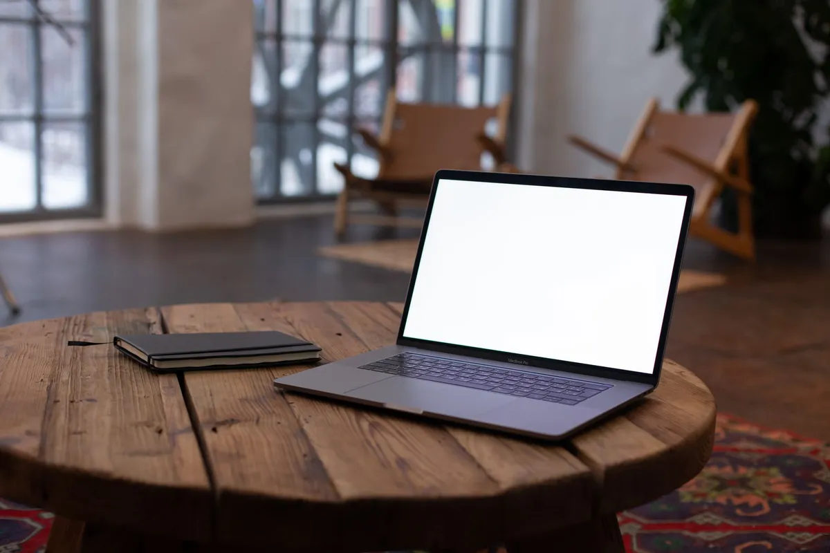 Un computer e un quaderno su un tavolo in legno in un ambiente domestico